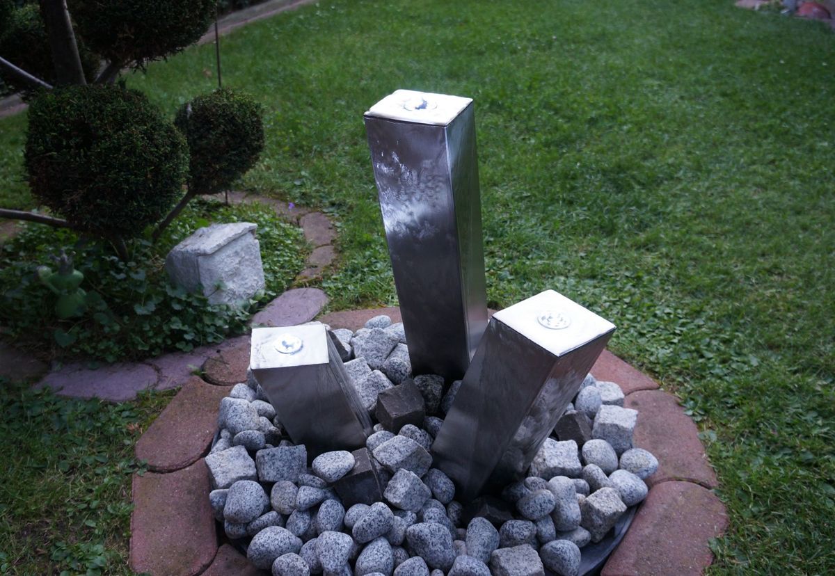 Ein Brunnen aus 3 Säulen aus Metall.