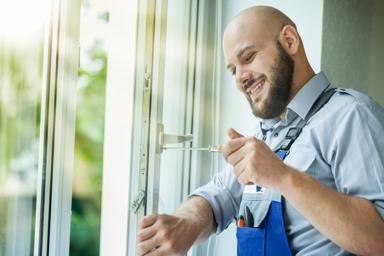 Ein Mann montiert einen Fenstergriff an einem geöffneten Fenster.