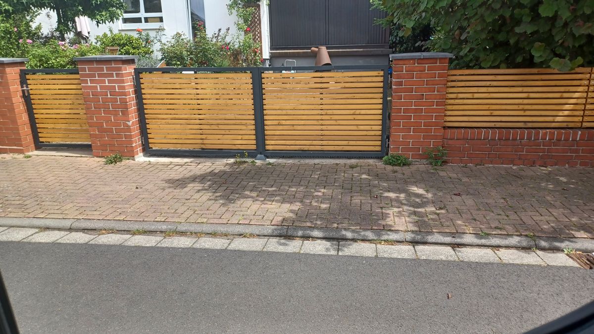 Ein Hoftor mit Metallrahmen und Holz-Einlagen.