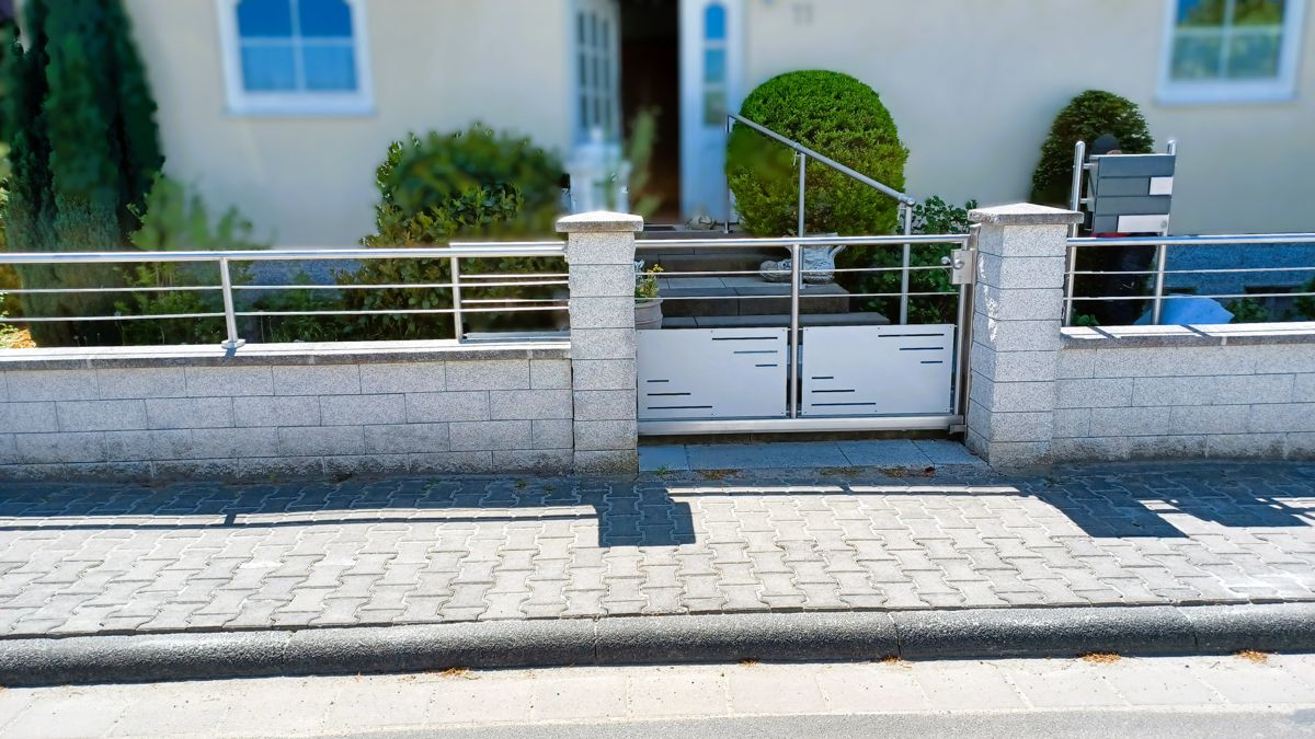 Ein metallenes Schiebetor vor einem Hauseingang.