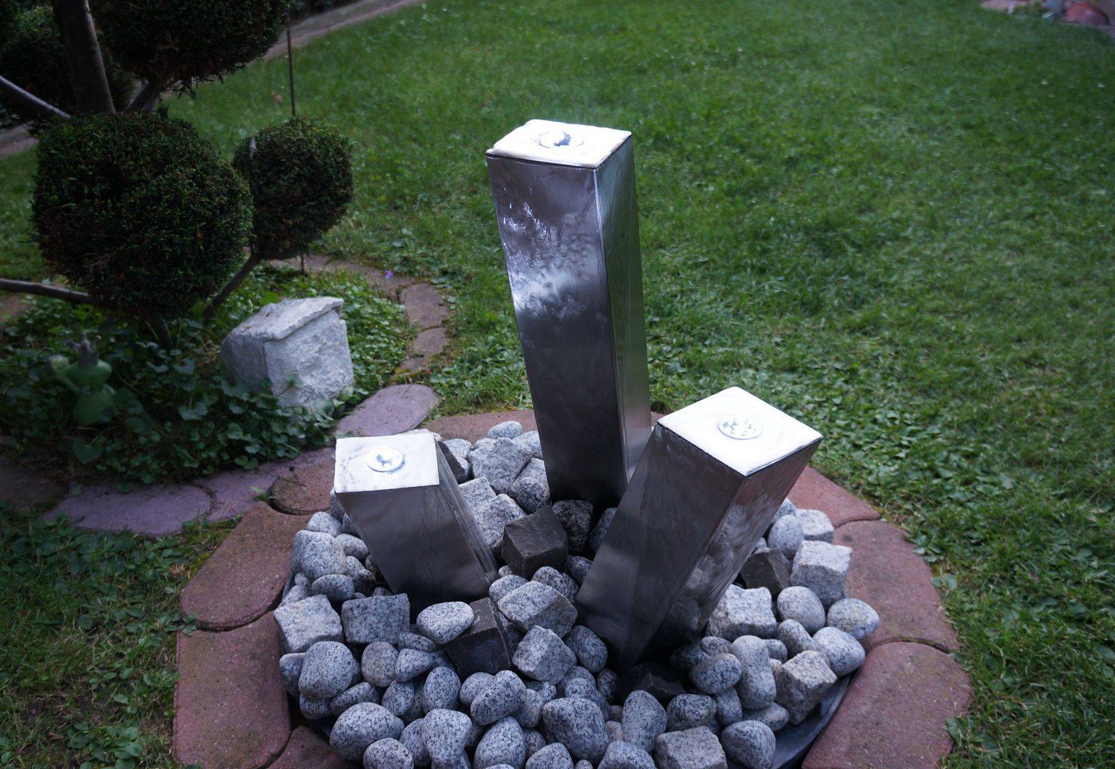 Ein Brunnen aus 3 Säulen aus Metall.
