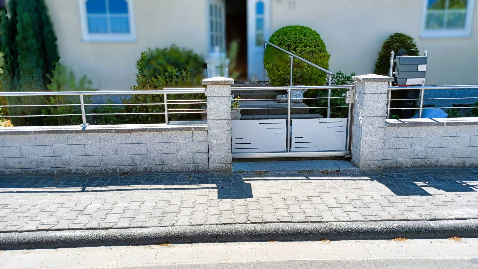 Ein metallenes Schiebetor vor einem Hauseingang.